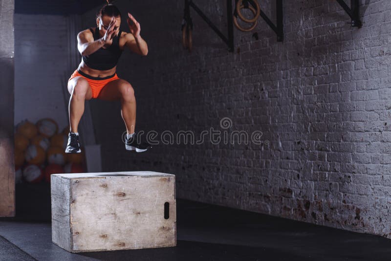 Woman box jumping at cross fit gym. athlete doing box jumps exercise at gym