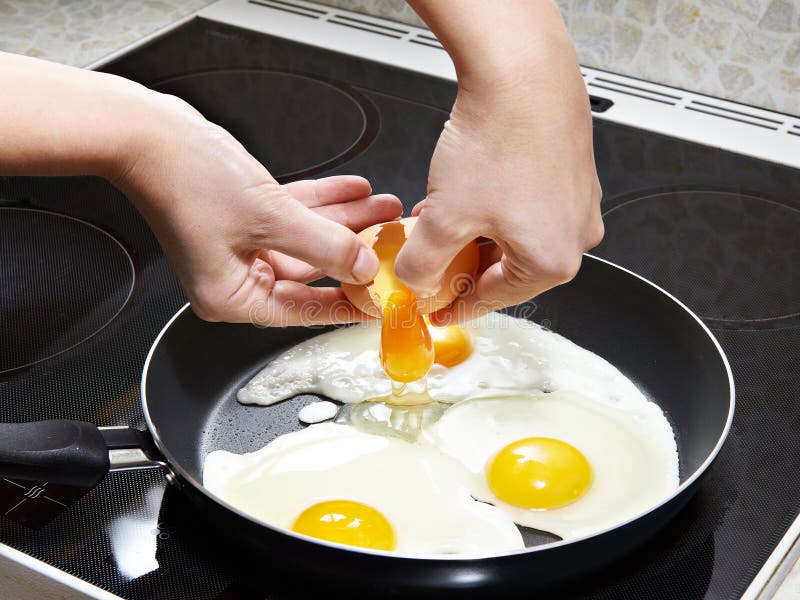Woman breaks an egg in fried eggs stock photo Woman breaks an egg in fried eggs stock photo