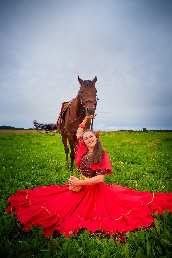 A Woman in a Bright Gypsy Dress and Image with a Horse in a Field with  Green Grass. a Model or Actress Posing in Nature with an Stock Photo -  Image of