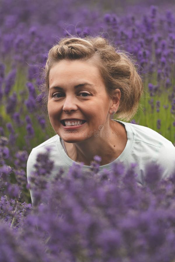 Woman with brunette hair smiles while posing in a field of lavender flowers in Sequim Washington stock photo Woman with brunette hair smiles while posing in a field of lavender flowers in Sequim Washington stock photo