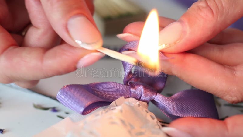 A woman cauterizes a match with a ribbon tied to a bow. Bouquet tied with a ribbon. Close-up shot