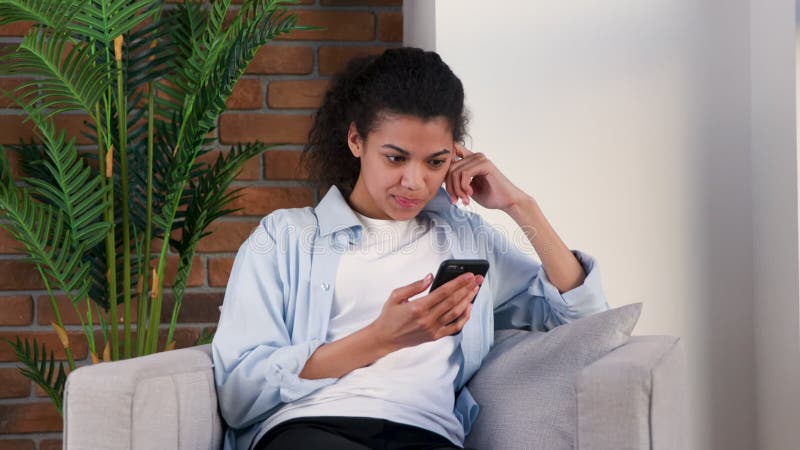 Woman chats with friends with her smartphone on a armchair