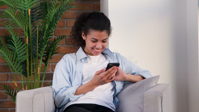 Woman chats with friends with her smartphone on a armchair