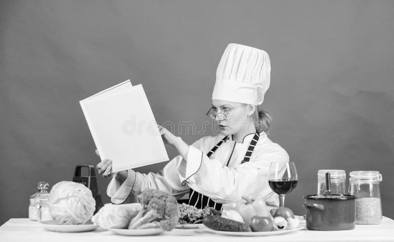Woman chef cooking healthy food. Girl read book top best culinary recipes. Culinary school concept. Female in hat and.