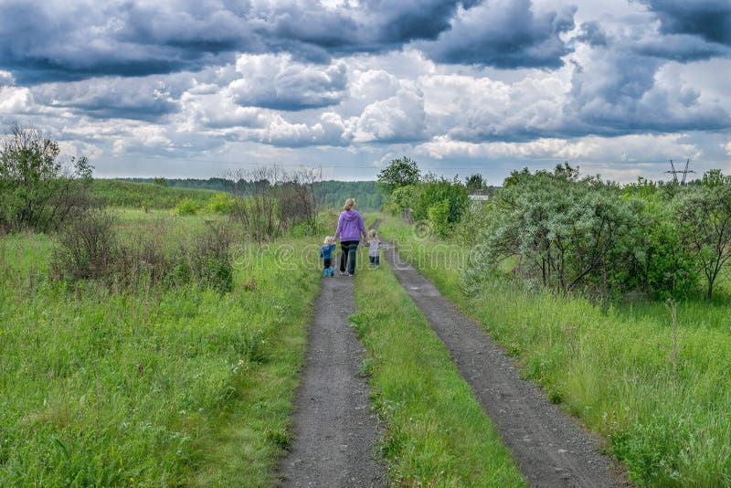 Woman and children walk on road under dark clouds royalty free stock photography Woman and children walk on road under dark clouds royalty free stock photography
