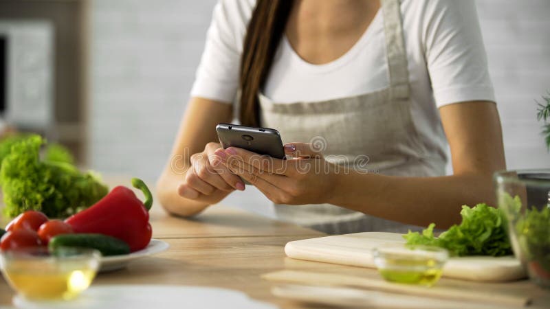 Woman choosing salad recipe on smartphone at the kitchen, cooking application royalty free stock image Woman choosing salad recipe on smartphone at the kitchen, cooking application royalty free stock image