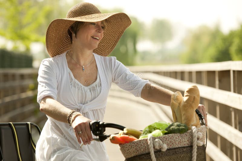 Woman cicyling with vegetables in her basket royalty free stock photo Woman cicyling with vegetables in her basket royalty free stock photo