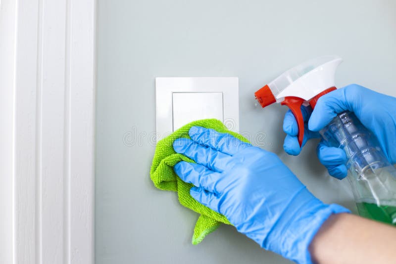 Woman Cleaning a Light Switch with a Disinfecting Spray Stock Image