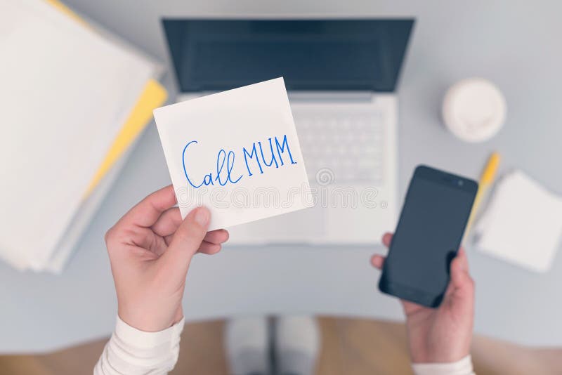 Woman clerk is sitting at office table holding note sticker with message call mum. Woman clerk is sitting at office table holding note sticker with message `call royalty free stock photos Woman clerk is sitting at office table holding note sticker with message call mum. Woman clerk is sitting at office table holding note sticker with message `call royalty free stock photos