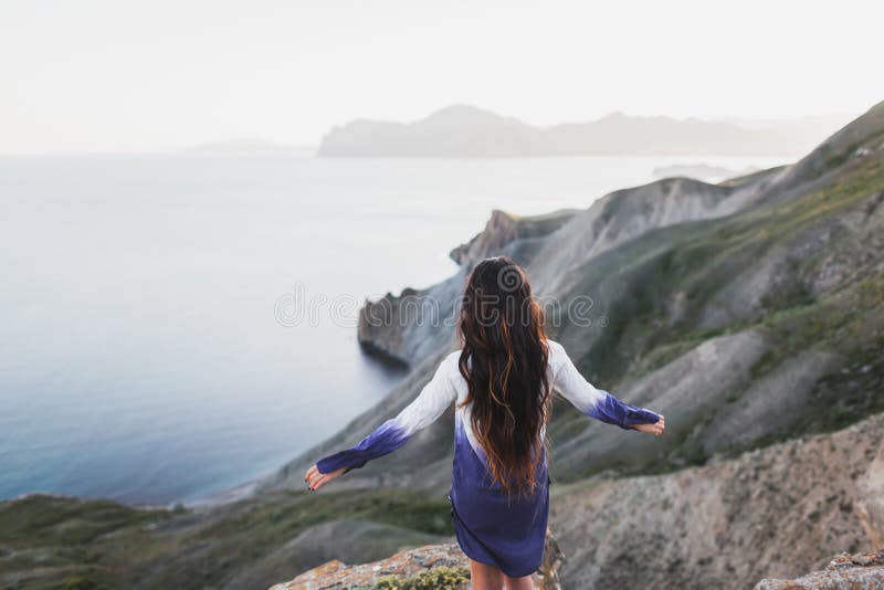 Woman on cliff with stunning view of sea coast with hills and mountains stock photos Woman on cliff with stunning view of sea coast with hills and mountains stock photos