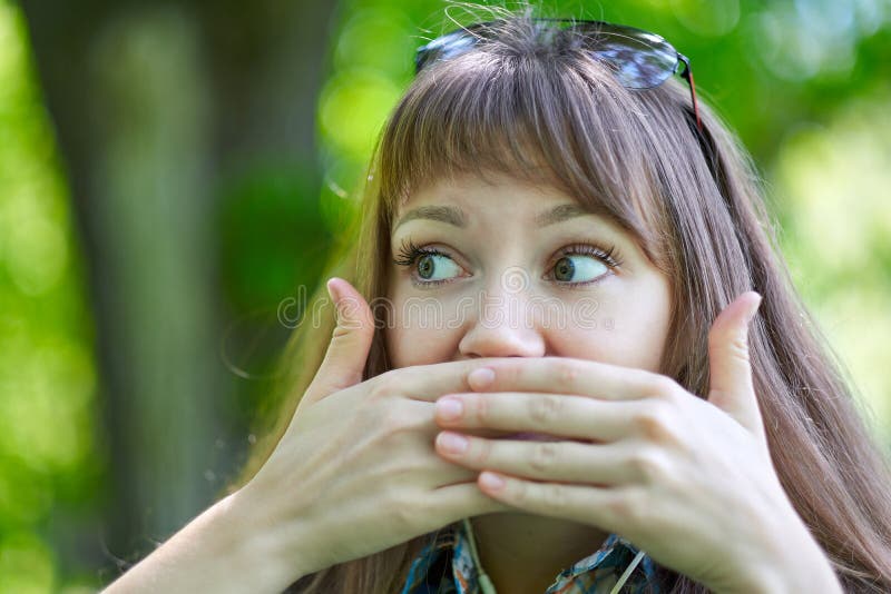 Woman close your mouth with your hands. Silence, gesture, no gossips, secret. Portrait in summer green park stock images Woman close your mouth with your hands. Silence, gesture, no gossips, secret. Portrait in summer green park stock images