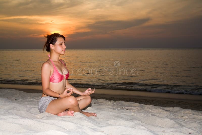 Woman closing eyes doing yoga on the beach