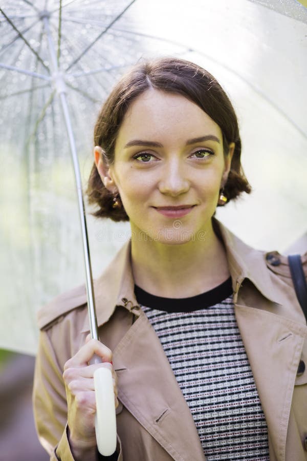 Woman at coat under umbrella since it rains.