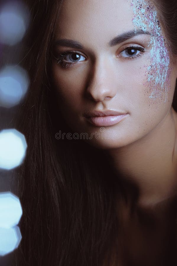 Beautiful woman with festive makeup in color spray powder and boke lights. Beautiful woman with festive makeup in color spray powder and boke lights