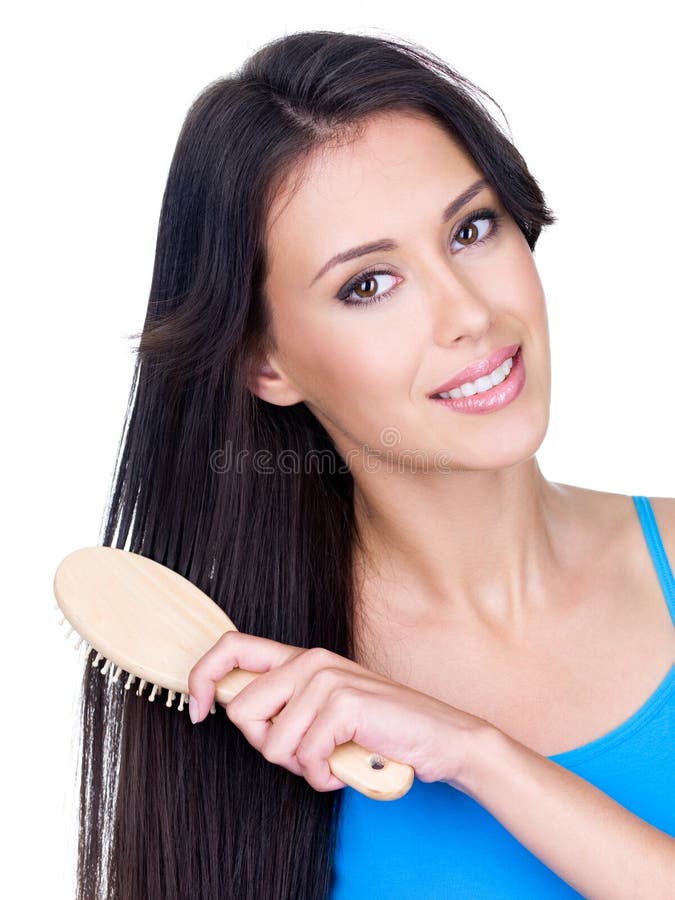 Smiling beautiful young woman combing her long brown hair with hairbrush - isolated. Smiling beautiful young woman combing her long brown hair with hairbrush - isolated