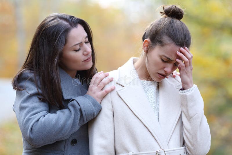 Woman comforting her sad friend in a park in winter