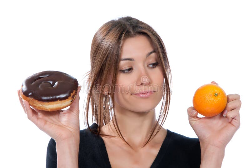 Woman comparing unhealthy donut and orange fruit