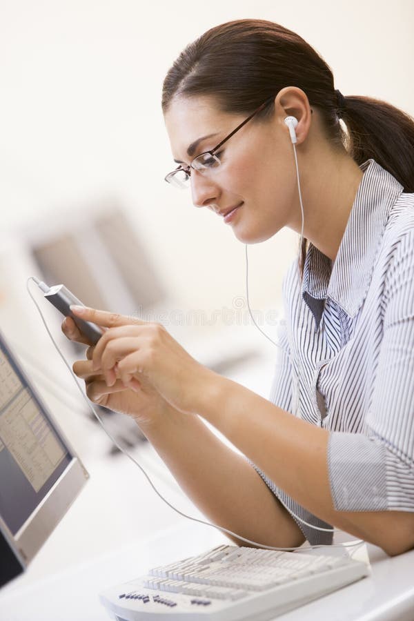 Woman in computer room listening to MP3 Player and smiling