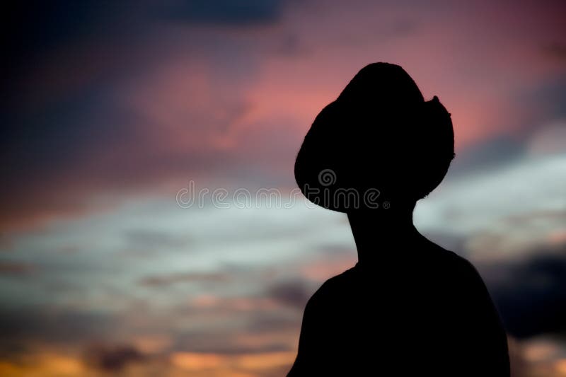 Woman in a cowboy hat silhouetted against a sunset