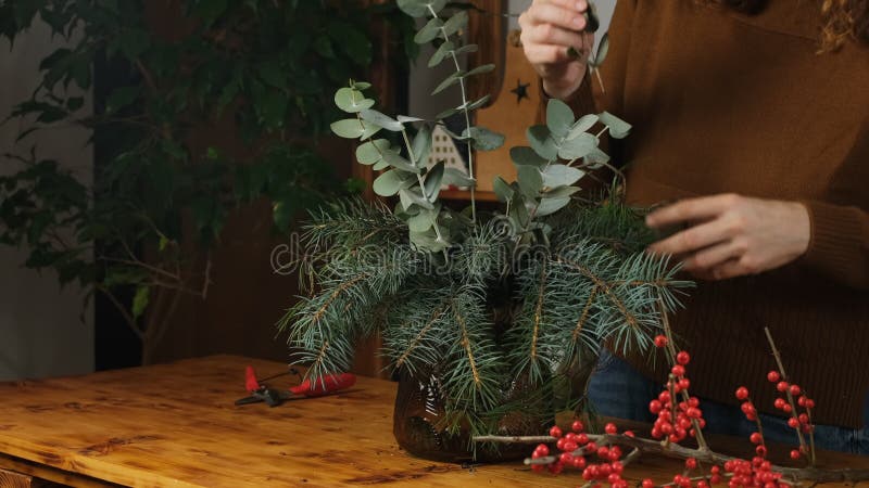 Woman creates floral decoration for winter holiday home decor.