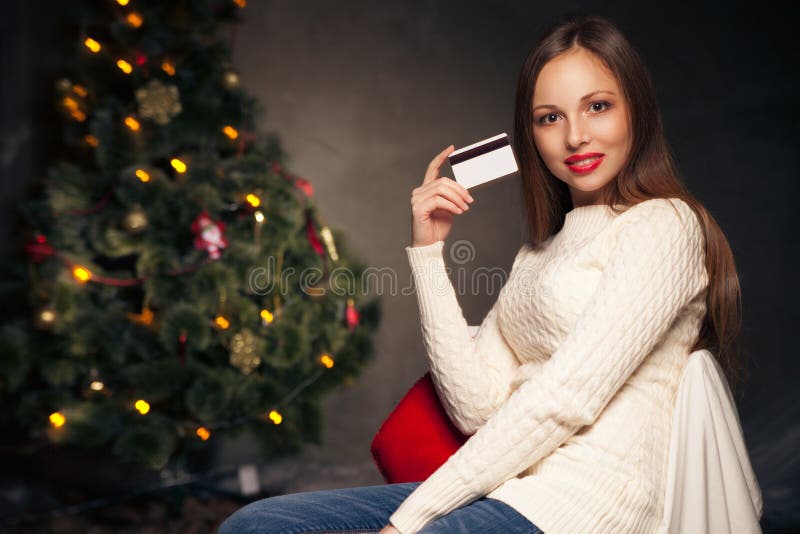 Woman with credit card in front of Christmas tree