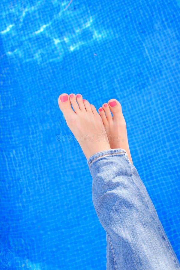 Woman crossed legs in blue jeans by swimming pool.