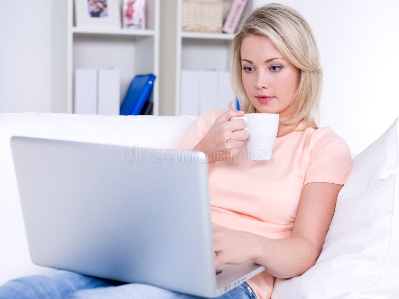 Beautiful young woman drinking coffee and using laptop. Beautiful young woman drinking coffee and using laptop