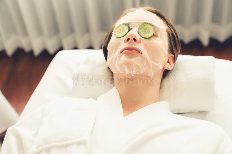 Woman customer indulges in rejuvenating with cucumber facial care. Quiescent