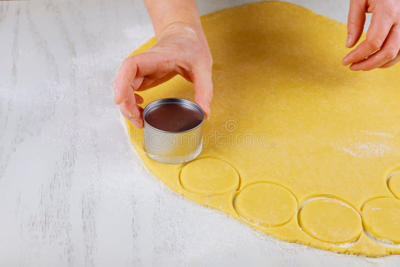 Woman cuts rolled dough for baking cookies on table