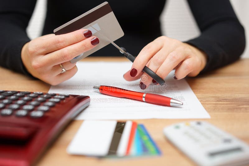 Woman is cutting credit card or bank card with scissors over con stock images Woman is cutting credit card or bank card with scissors over con stock images