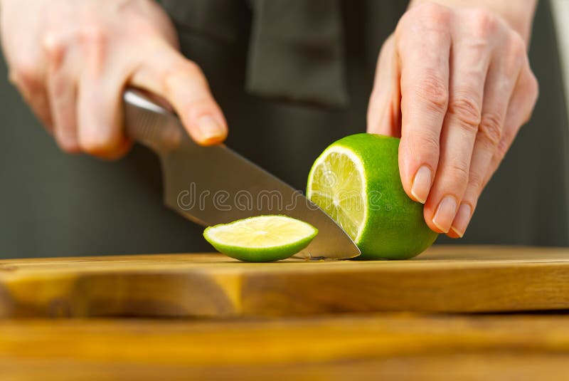 Woman cutting lime in kitchen, lemon water, Refreshing Water with lime and lemon, healthy eating concept