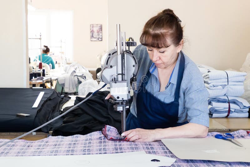 A Woman with a Cutting Machine at a Sewing Industrial Workplace. Fabric