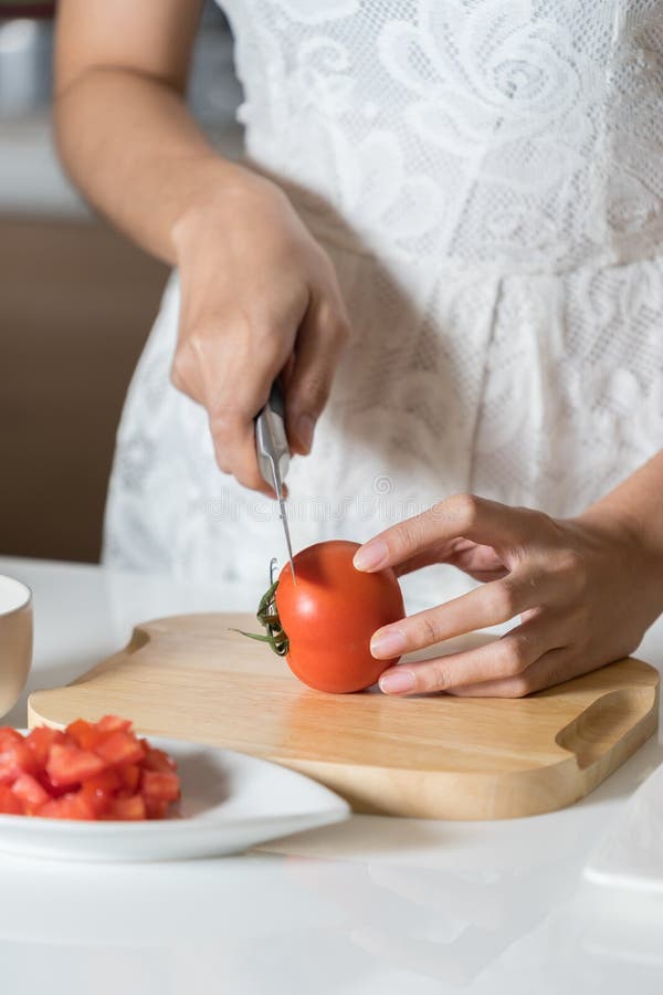 Woman cutting tomato on wood board. stock photography Woman cutting tomato on wood board. stock photography
