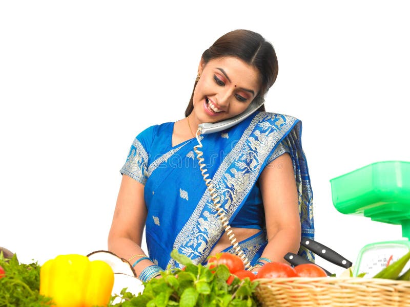 A woman cutting vegetables and talking in the phon
