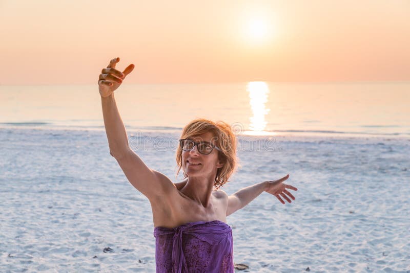 Woman dancing on sand beach romantic sky at sunset, front view, golden sunlight, real people. Indonesia, Kei islands, Moluccas Maluku