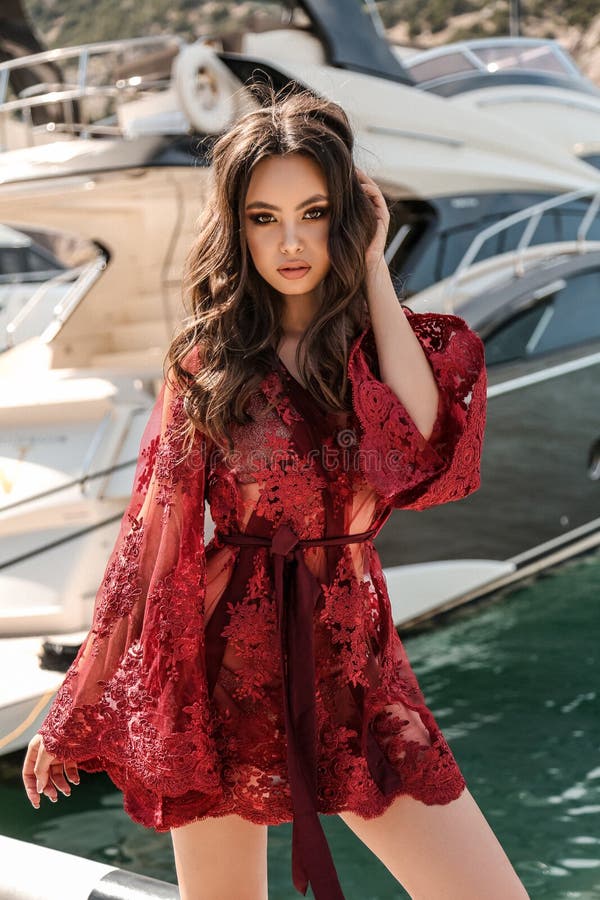 Woman with dark hair in elegant swimming suit posing near yachts