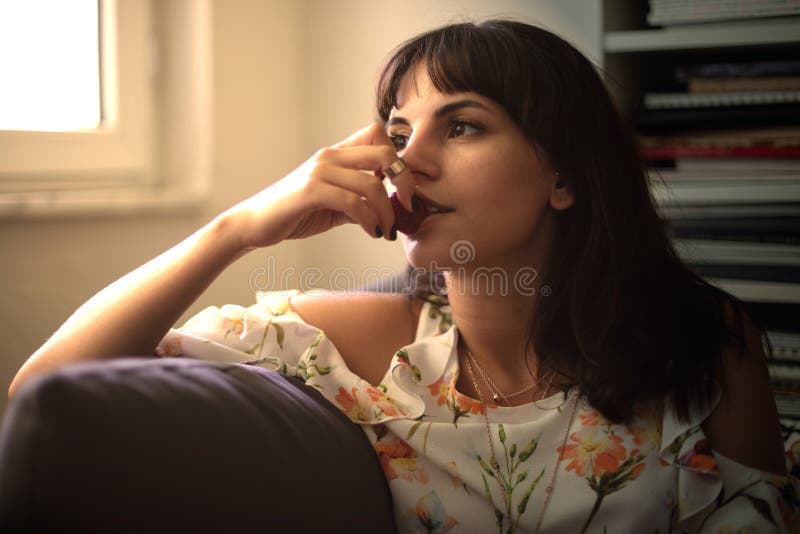Woman daydreaming and eating a ripe strawberry on a sofa royalty free stock image Woman daydreaming and eating a ripe strawberry on a sofa royalty free stock image
