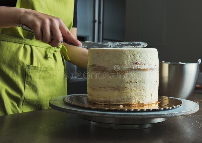 Woman decorating a delicious layered sponge cake with icing cream royalty free stock photo