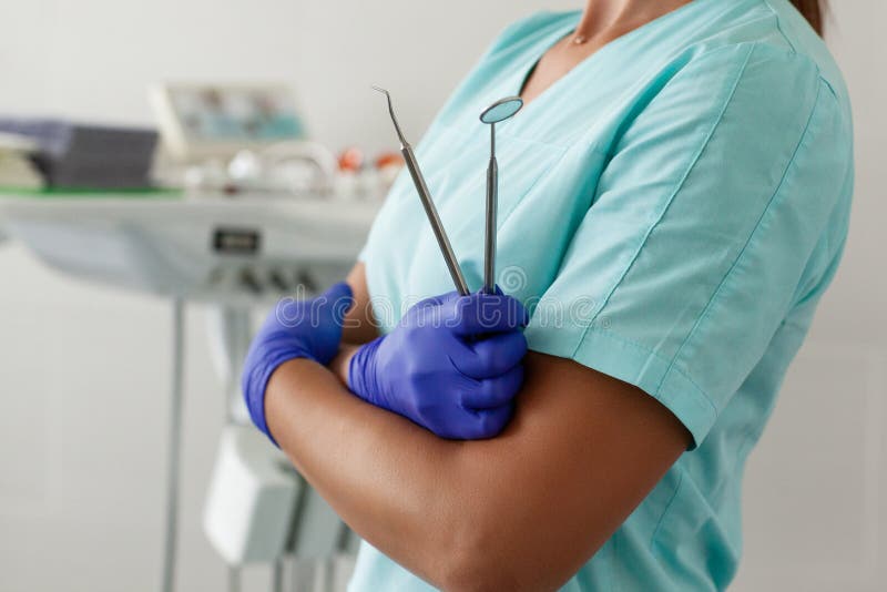 Woman dentist derzhit professional dentist tools in the dental office, mirror and curved tweezers royalty free stock photo Woman dentist derzhit professional dentist tools in the dental office, mirror and curved tweezers royalty free stock photo