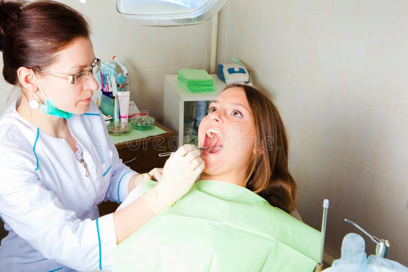 Woman dentist making a review of patient mouth