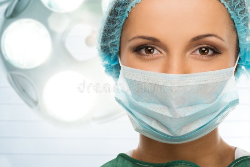 Giovane donna medico nel cappuccio e una maschera per il viso in sala operatoria interni.