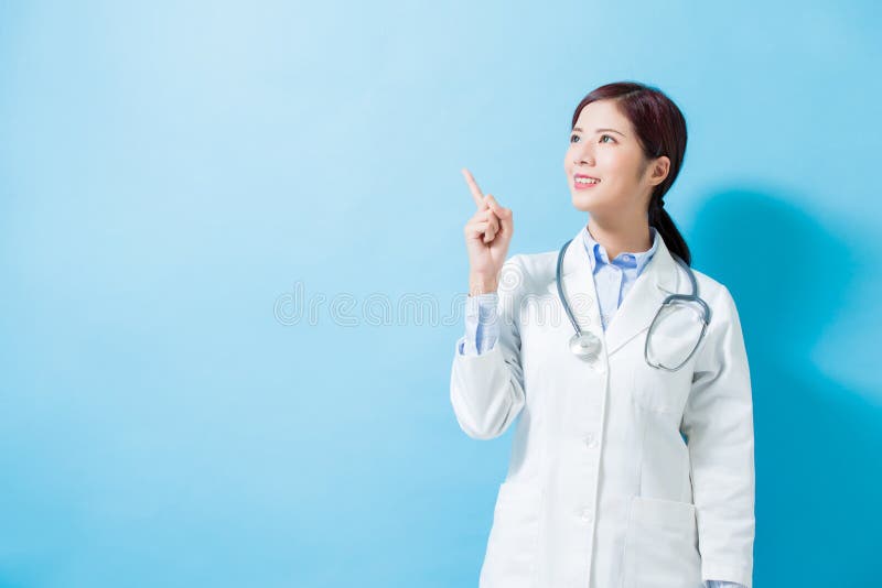 Woman doctor pointing something and look somewhere on the blue background