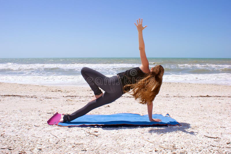 Woman doing yoga on beach in side plank