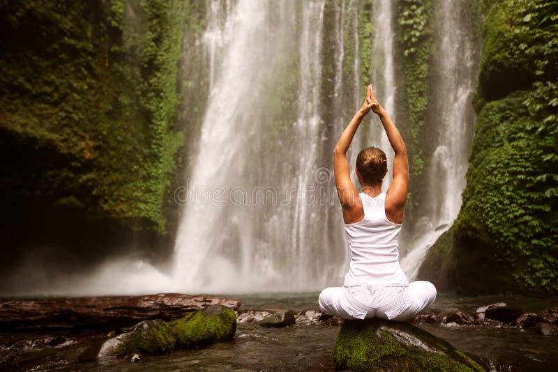 Woman doing yoga near waterfall