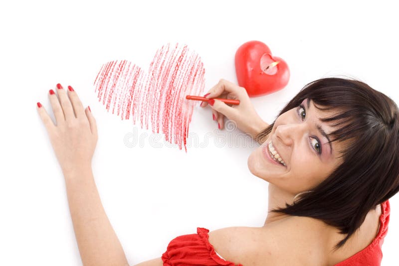 Beautiful young woman with wax crayon lying on floor and drawing heart-shape. Beautiful young woman with wax crayon lying on floor and drawing heart-shape