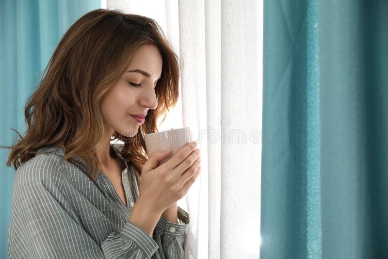 Woman Drinking Coffee Near Window With Beautiful Curtains Stock Photo