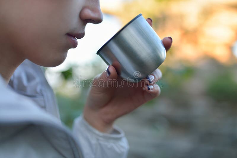 Woman drinking hot tea from a thermos cup closeup stock photos Woman drinking hot tea from a thermos cup closeup stock photos
