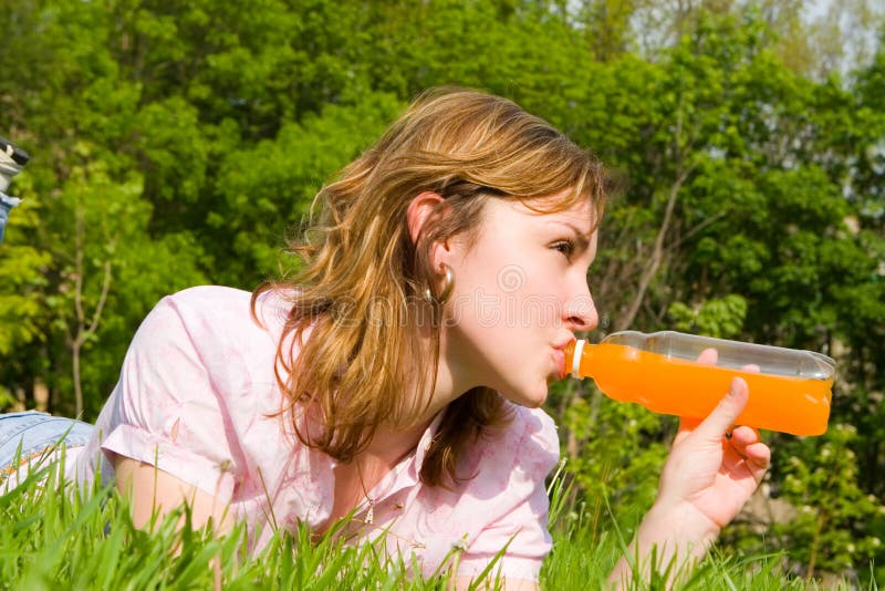 Woman drinking juice on the summer glade