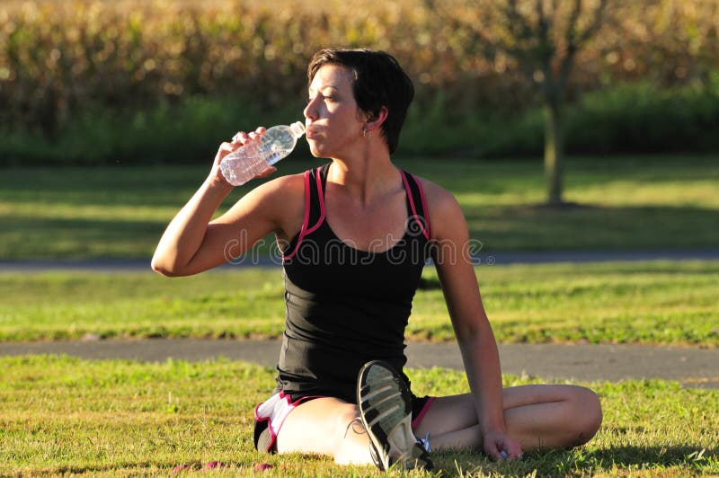 Mujer joven bebiendo Agua después externo.