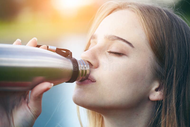 Woman drinking water, using stainless steel instead of single-use plastic bottle